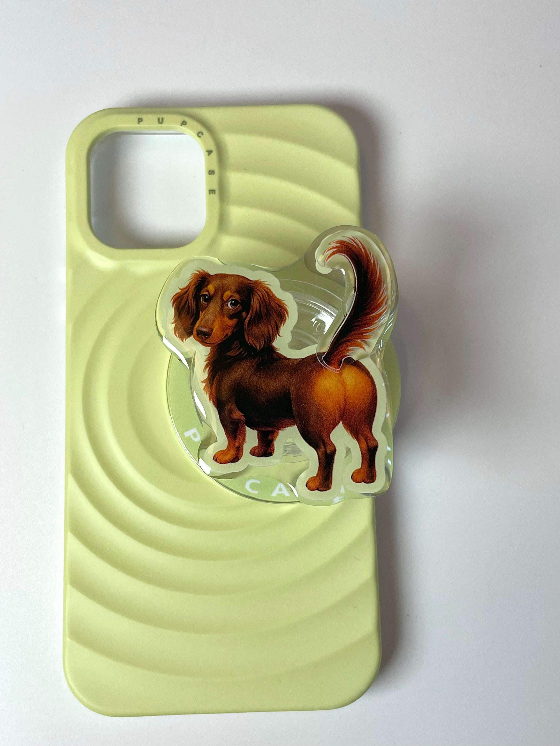 dachshund phone grip by pupcase placing on top of a yellow magsafe phone case